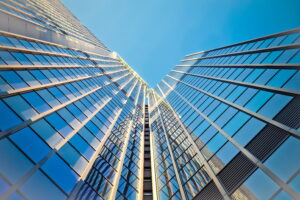 Upward shot of glass skyscraper and blue skies.