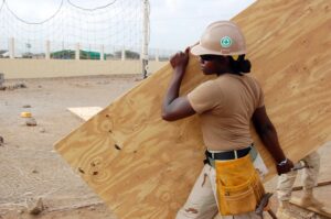 Female construction worker carrying a piece of wood on the work site.